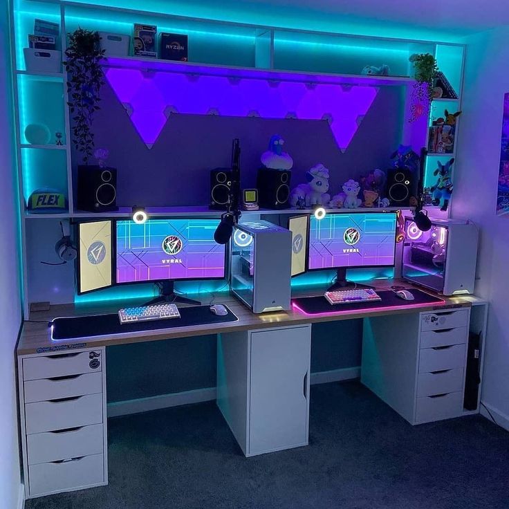 two computer monitors sitting on top of a desk in front of a purple and blue wall