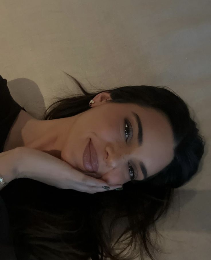 a woman laying on top of a bed next to a white wall