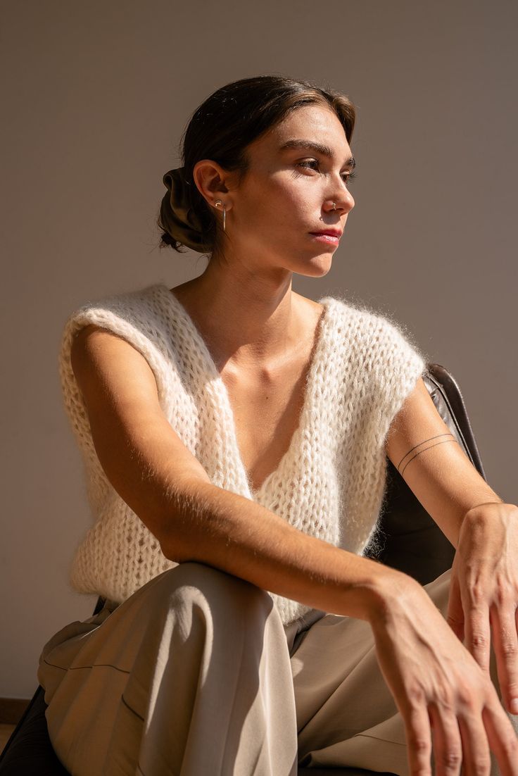 Handcrafted in our premium kid mohair blend, the Mohair Wrap Vest is incredibly soft, lightweight, and airy. Its reversible design offers multiple styling options, featuring a sleek boatneck on one side and a deep V-neck on the other. Wraps at the side for a flattering, form-enhancing fit. Whether paired with a turtleneck or worn solo, it effortlessly transitions between seasons. Wear it as a backless statement piece or switch to the V-neck side for a more casual look. A versatile, hand-knit ves Mohair Top, Wrap Vest, White Vest, Vest Designs, Vest White, Vest Outfits, Style Expert, Sleeveless Sweater, Look Plus