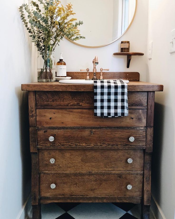 a bathroom with a sink, mirror and checkered towel hanging on the dresser in front of it