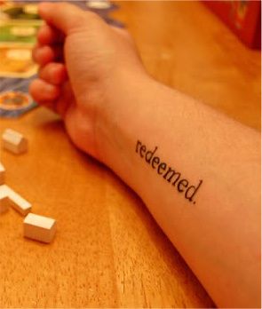 someone has their arm tattooed with the word redeemed on it and white cubes scattered around them