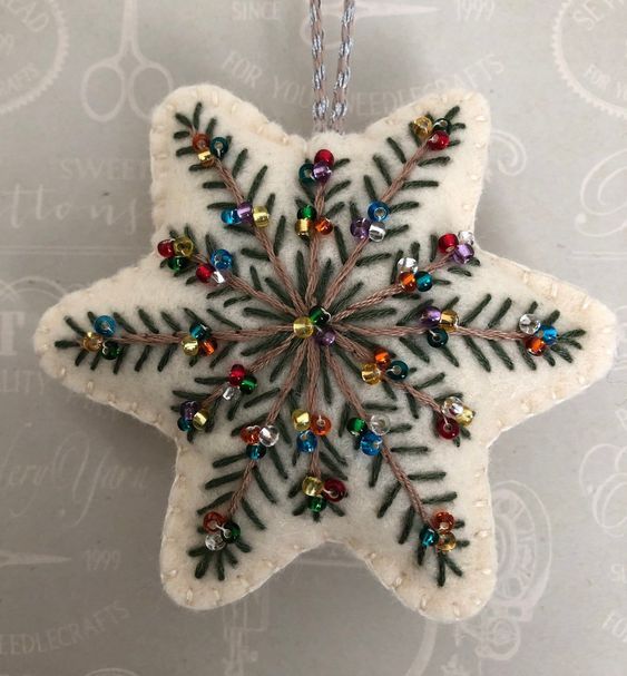 a white snowflake ornament with multicolored beads and leaves on it