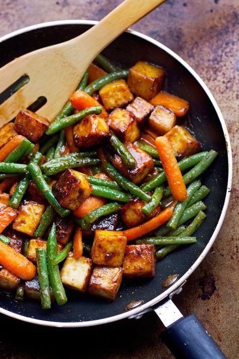 a pan filled with cooked vegetables and a wooden spoon