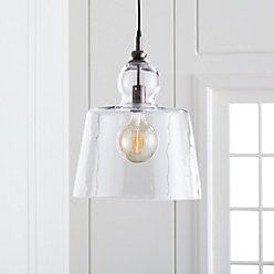 a clear glass pendant light hanging from a ceiling fixture in a room with white walls