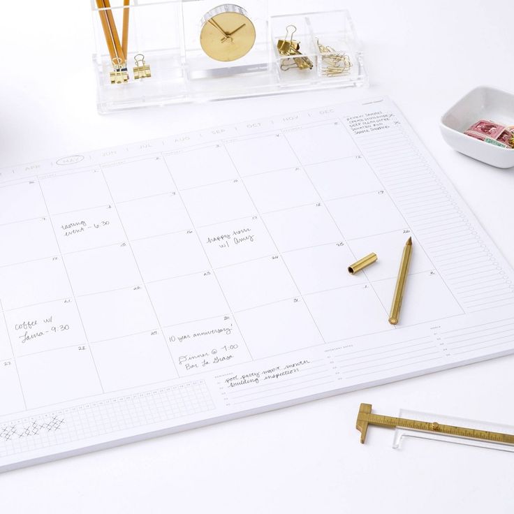 a desk with a calendar, pen, pencils and other office supplies on it