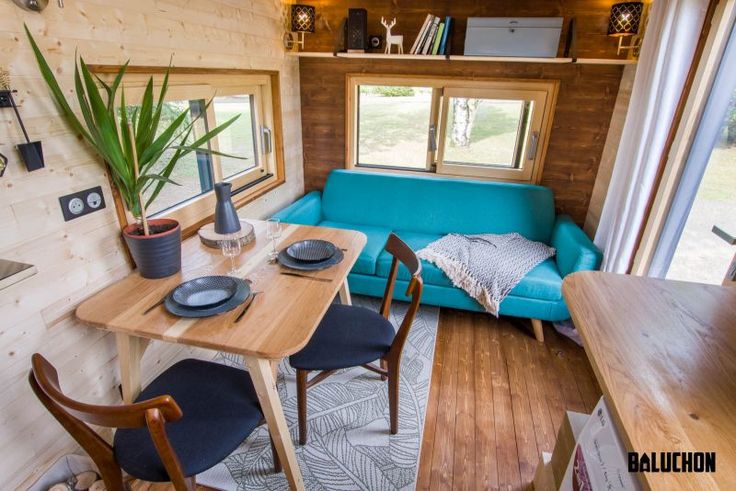 the interior of a tiny home with blue couch and wooden table in front of it