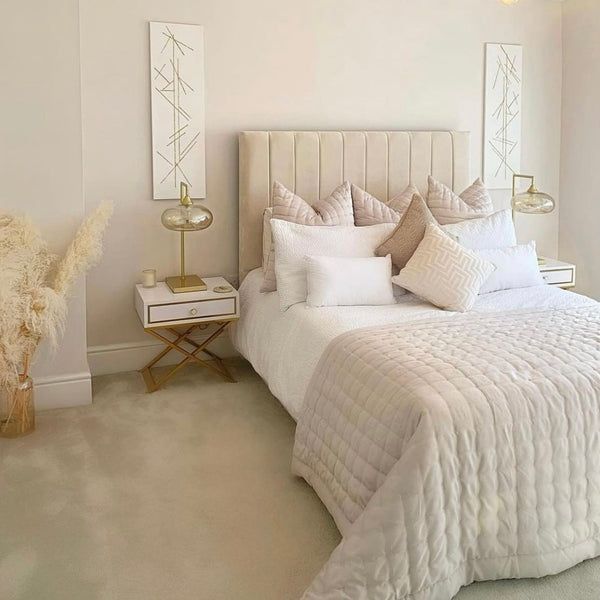 a white bed sitting in a bedroom next to a mirror on the side of a wall