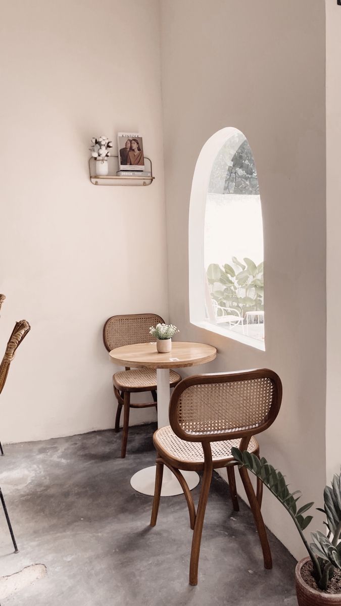 two chairs and a table in a small room with an arched window on the wall