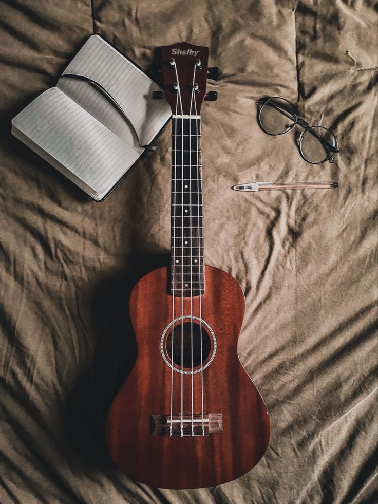 a ukulele and an open book on a bed