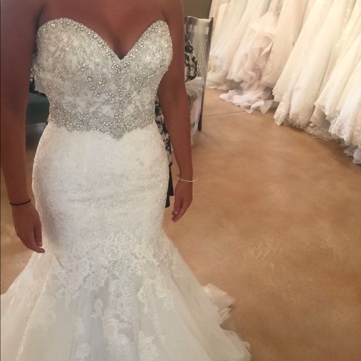 a woman in a wedding dress looking at herself in the mirror with her hand on her hip