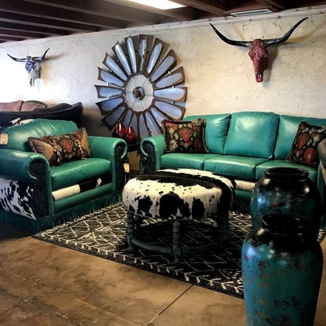 a living room filled with green couches and cow heads on the wall above them