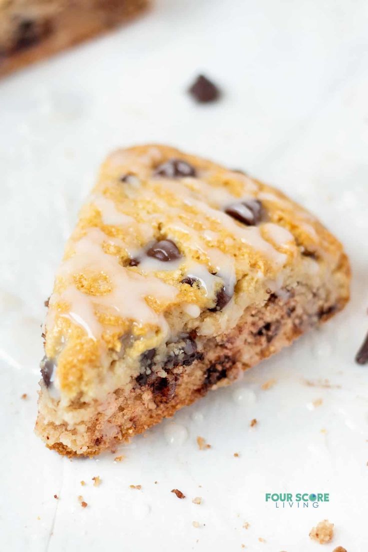 a piece of chocolate chip cookie with icing on it sitting on a white surface