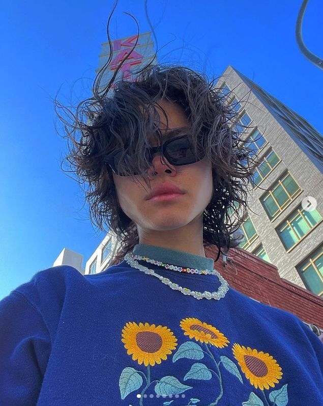 a woman with sunflowers on her sweater and sunglasses