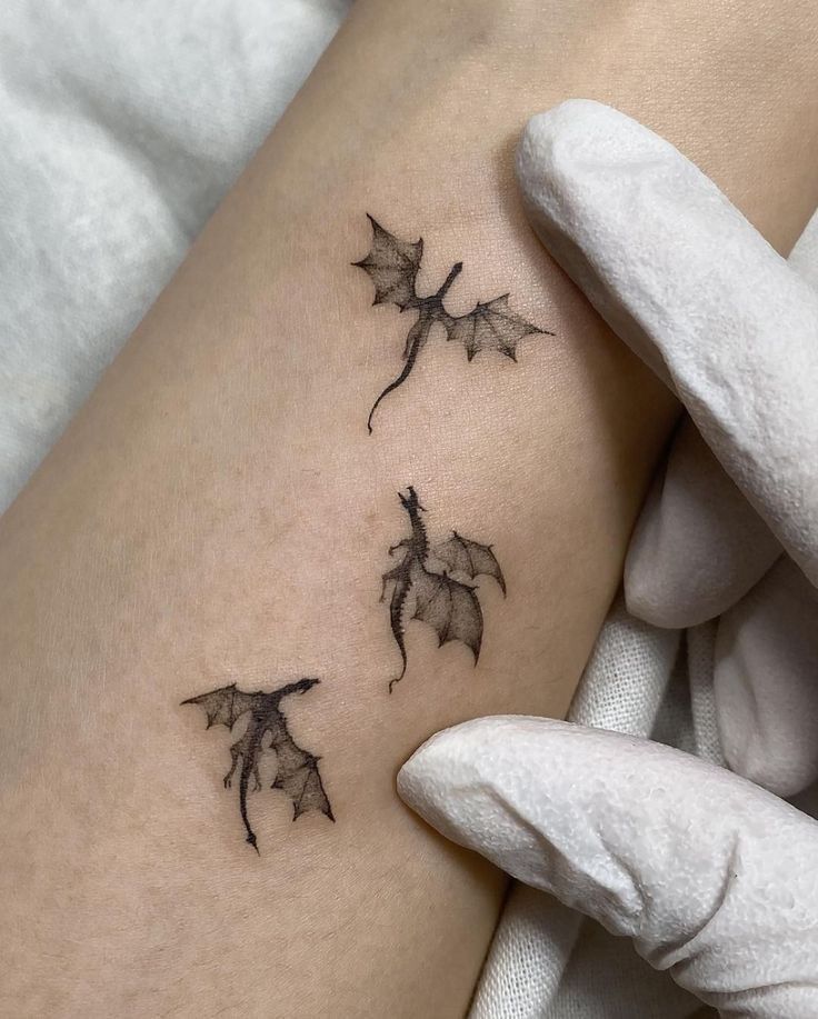 a woman's thigh with three small bats on the back of her leg and one is