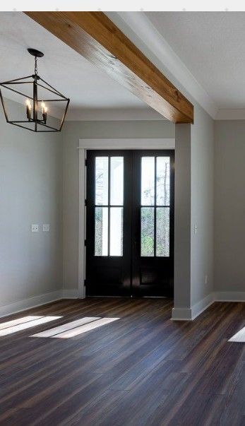 an empty living room with wood floors and black doors