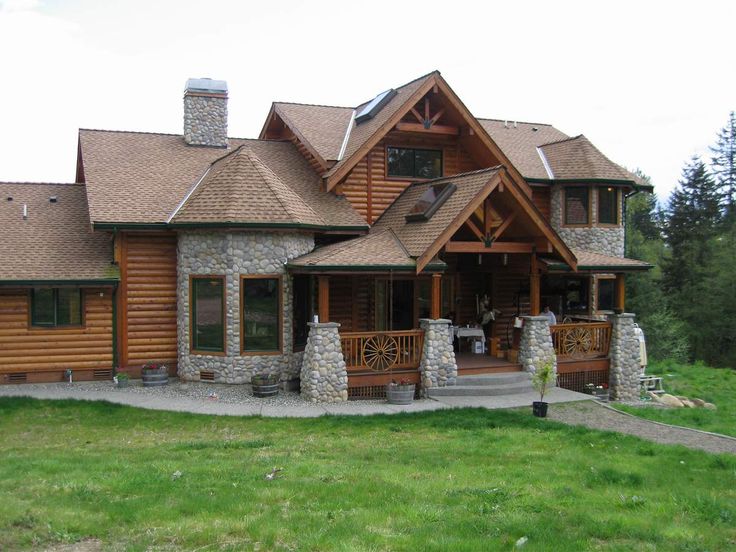 a large log home sitting on top of a lush green field