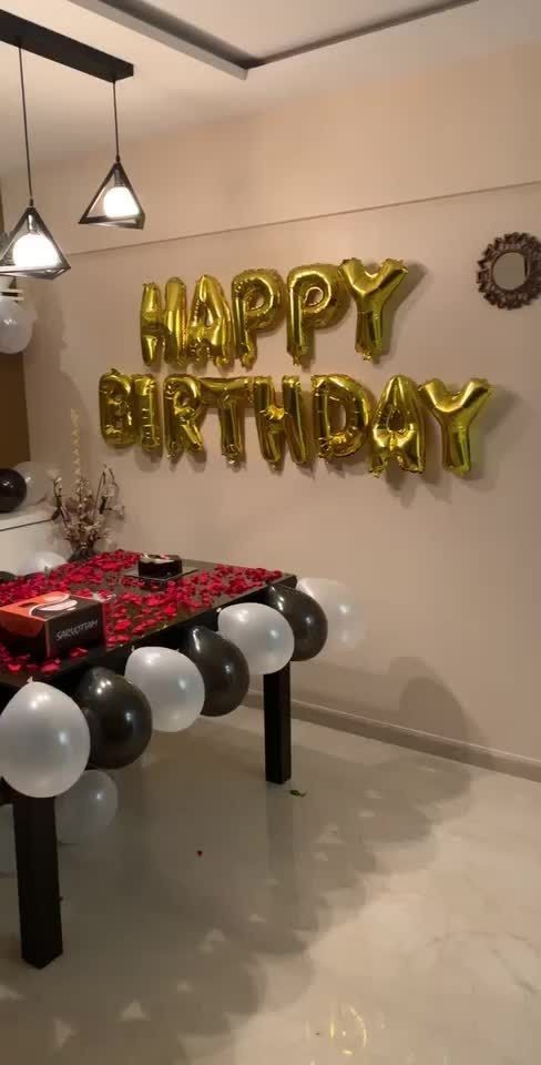 a birthday party with balloons and presents on a table in front of the sign that says happy birthday