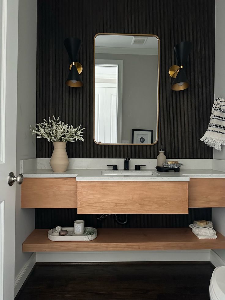 a bathroom vanity with a large mirror above it and plants on the counter in front of it