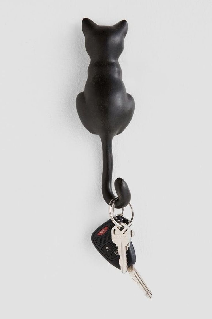 a black cat shaped key holder hanging on a wall