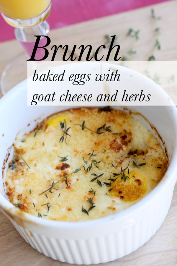 an egg casserole with goat cheese and herbs in a white dish next to a glass of orange juice