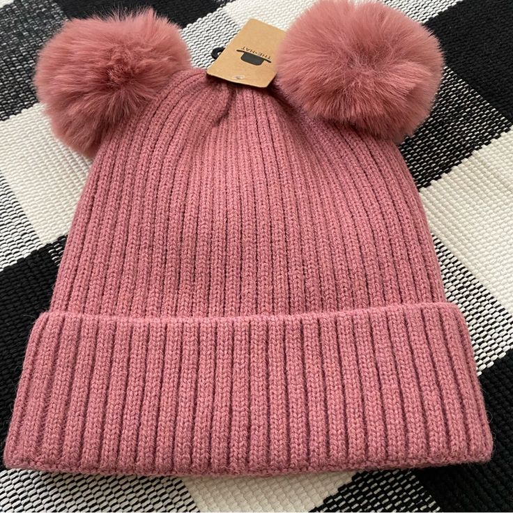 a pink hat with two pompoms on it