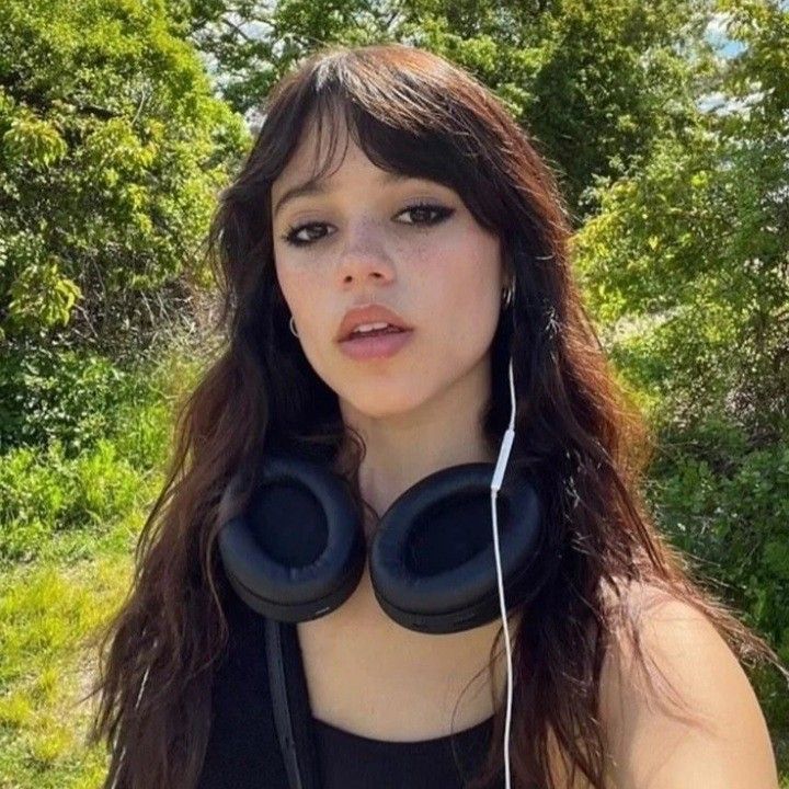 a woman wearing headphones standing in front of trees