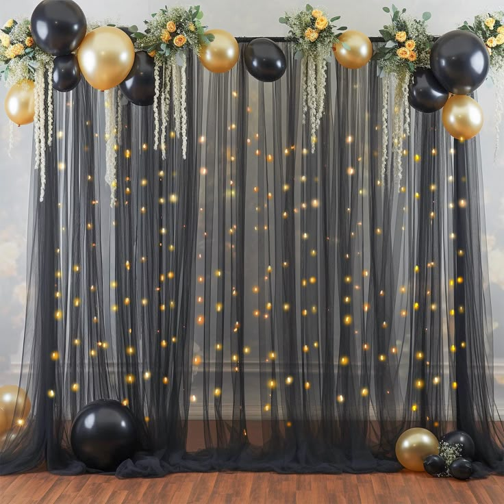 black and gold balloons are hanging from the sheer drapes in front of a backdrop