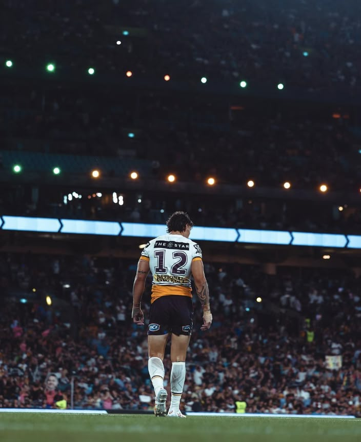 a man standing on top of a soccer field in front of a stadium filled with people