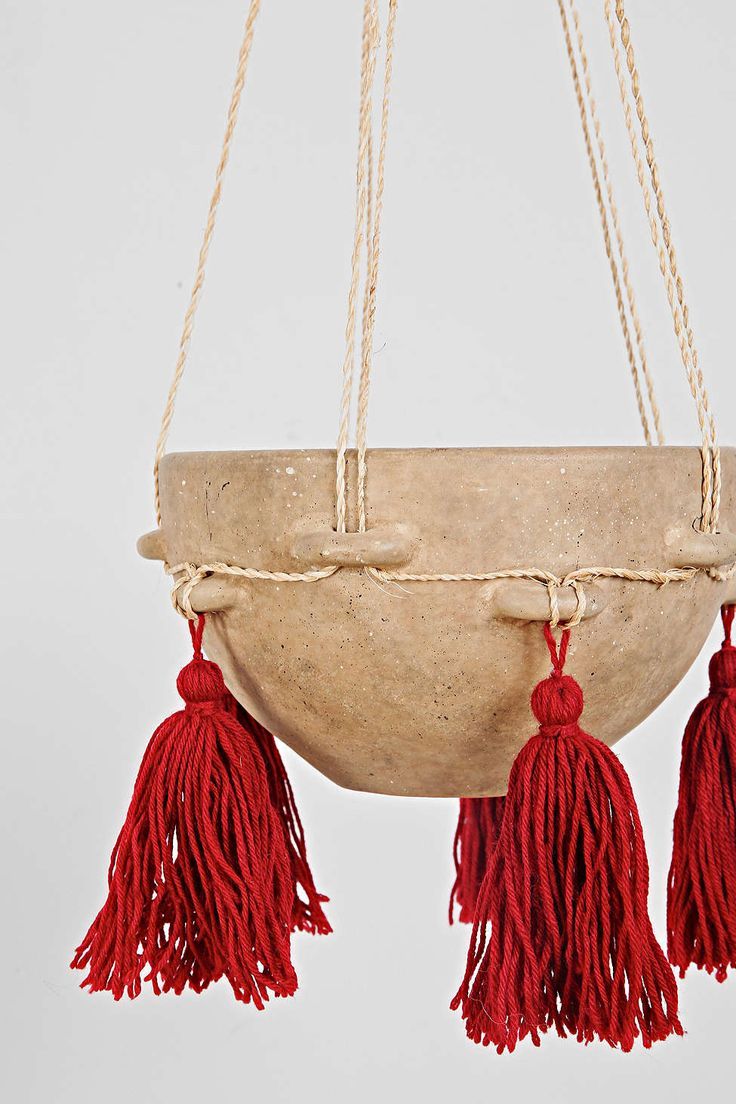 a hanging planter with red tassels on it