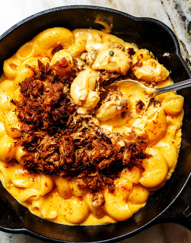 a skillet filled with macaroni and cheese on top of a marble counter