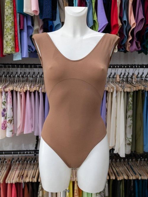 a mannequin wearing a brown bodysuit in front of clothes on hangers