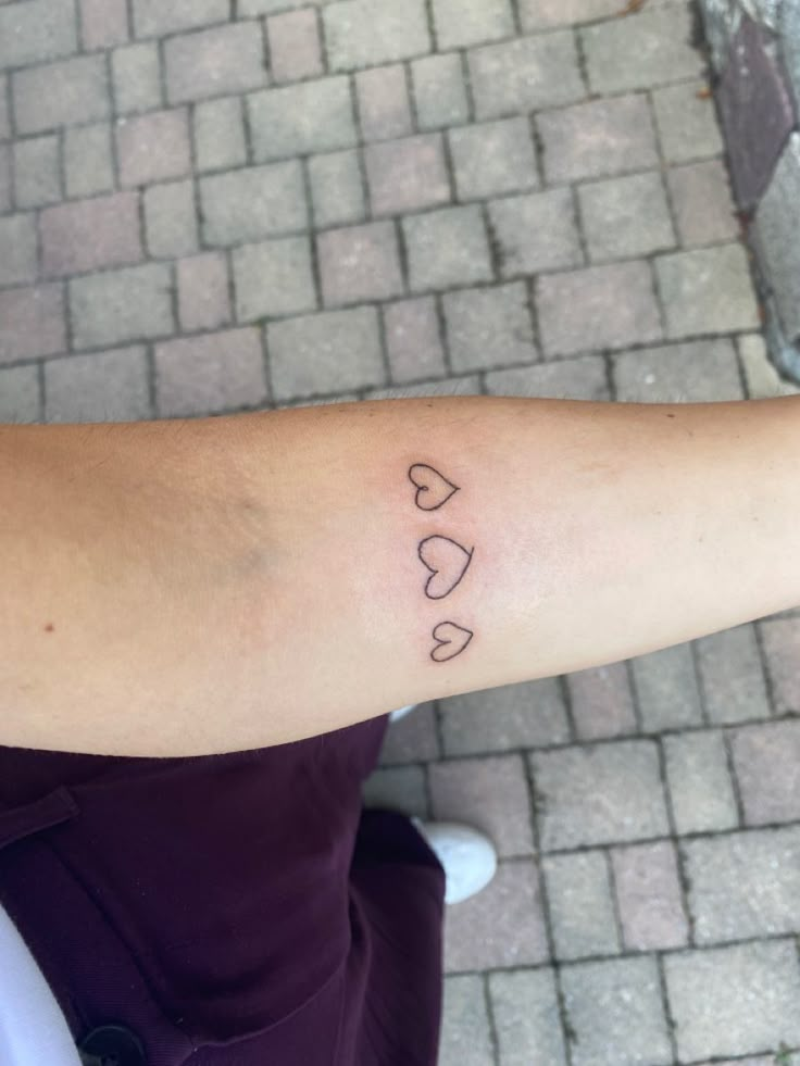 a woman's arm with the word love on it and two hearts drawn in black ink