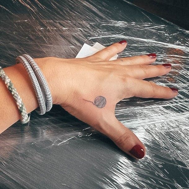 a woman's hand with a small tattoo on her left wrist and the other arm