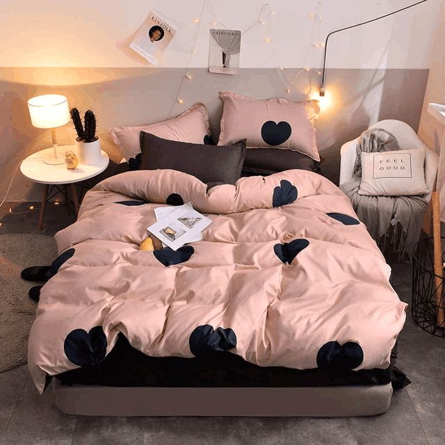 a bed with pink and black comforter in a bedroom next to a night stand