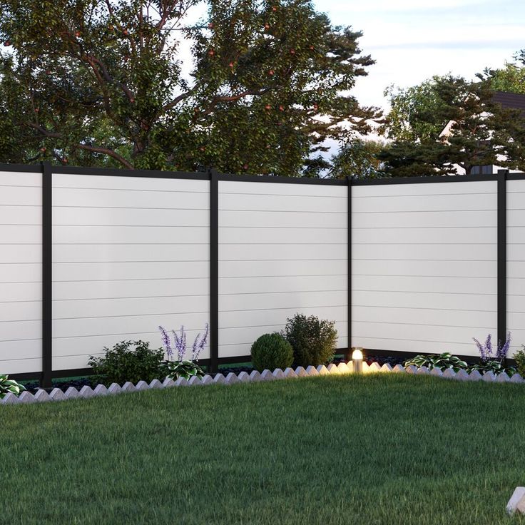 a white privacy fence in the middle of a grassy area