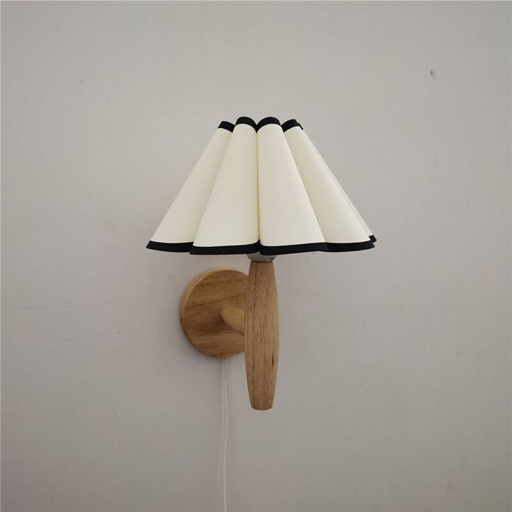 a lamp that is on the wall next to a wooden light fixture with a black and white shade