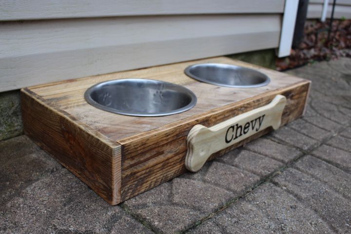 a dog feeder station with two metal bowls on the bottom and one is made out of wood