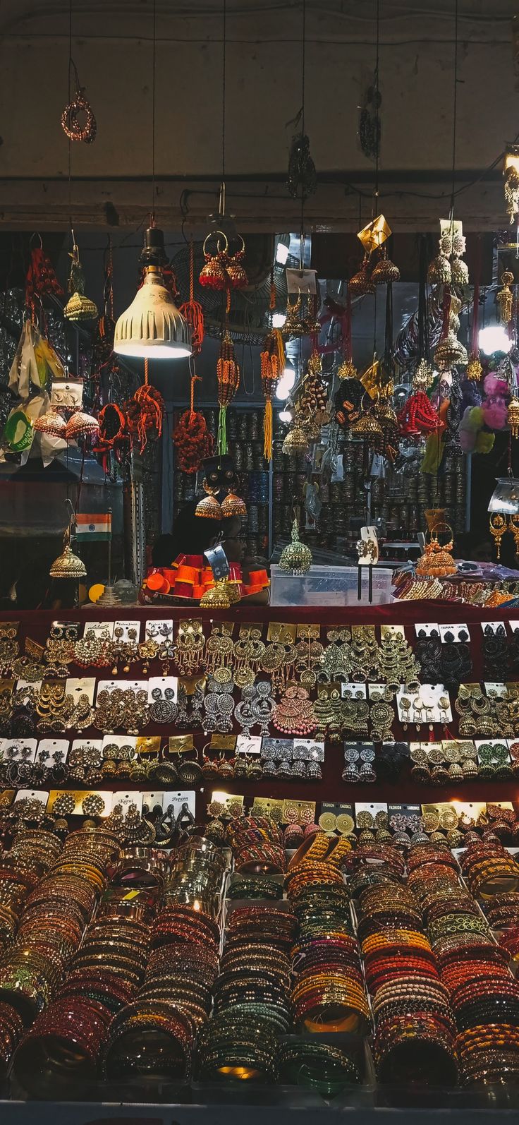 an assortment of bracelets and necklaces on display in a store window at night