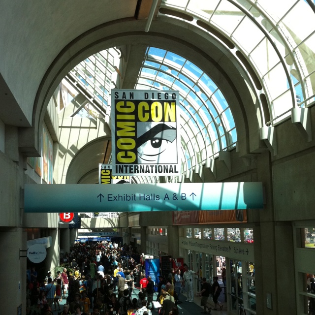 an indoor convention hall filled with lots of people and signs that read comiccon international