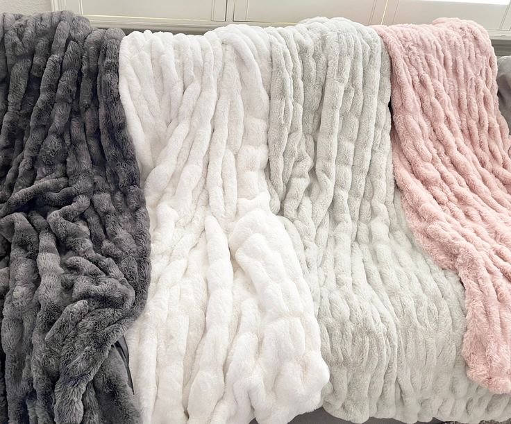 four blankets are lined up on a window sill