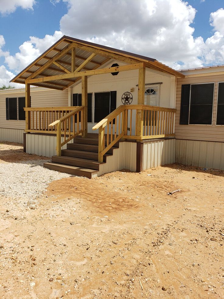 a mobile home with stairs leading up to the front door and covered porchs on both sides