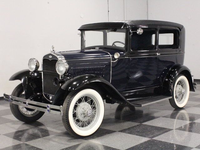 an old model black car on a checkered floor