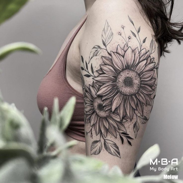 a woman with a sunflower tattoo on her arm and shoulder, next to a potted plant