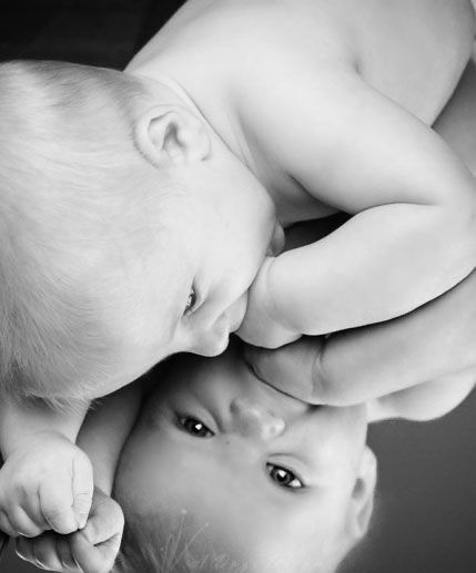 a baby is being held up to its mother's face with her head in the mirror