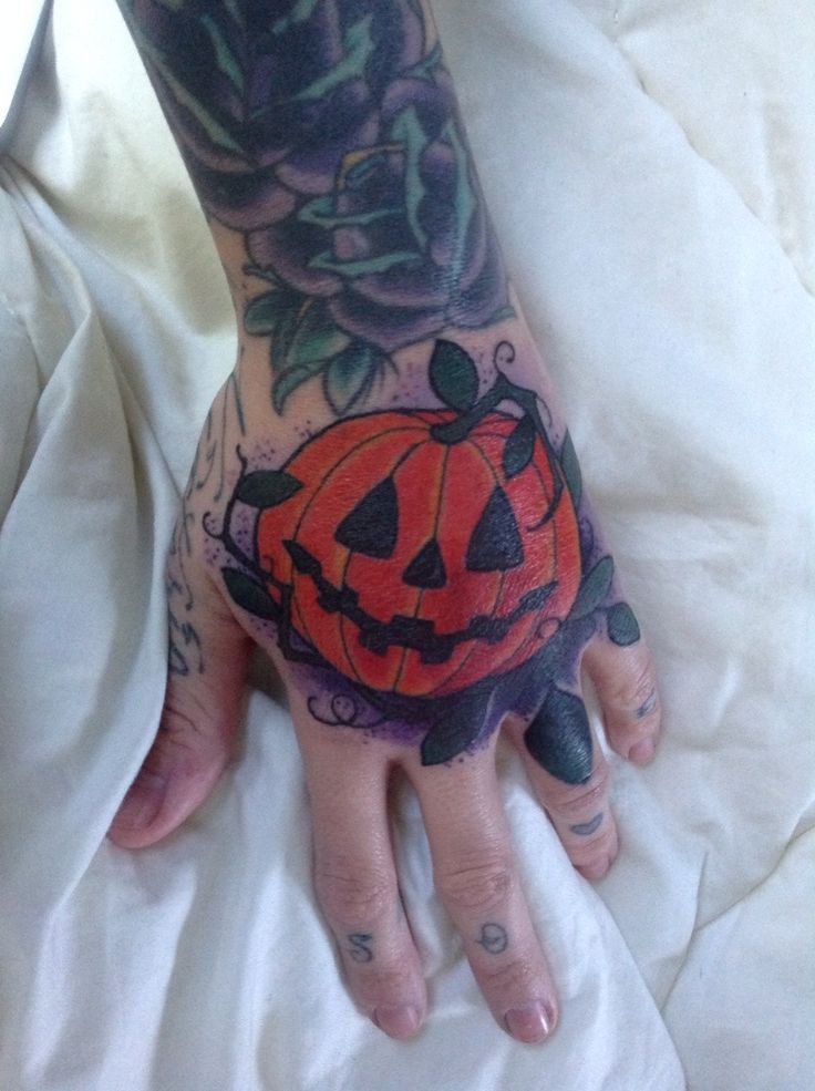 a hand with a tattoo on it and a jack - o'- lantern in the middle