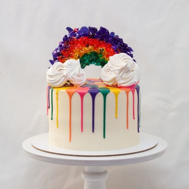 a cake with white frosting and rainbow drips on top is sitting on a plate