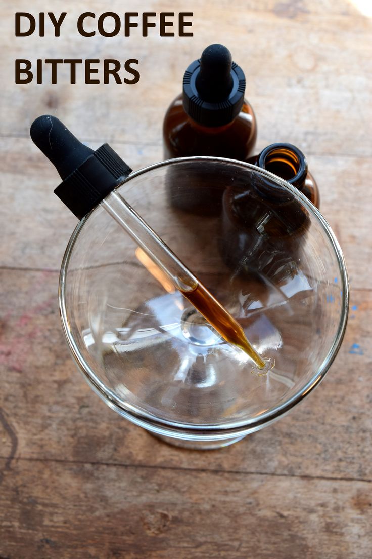 a glass bowl filled with liquid and two bottles next to each other on top of a wooden table