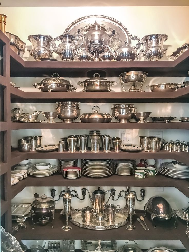 the shelves are filled with silver dishes and pans