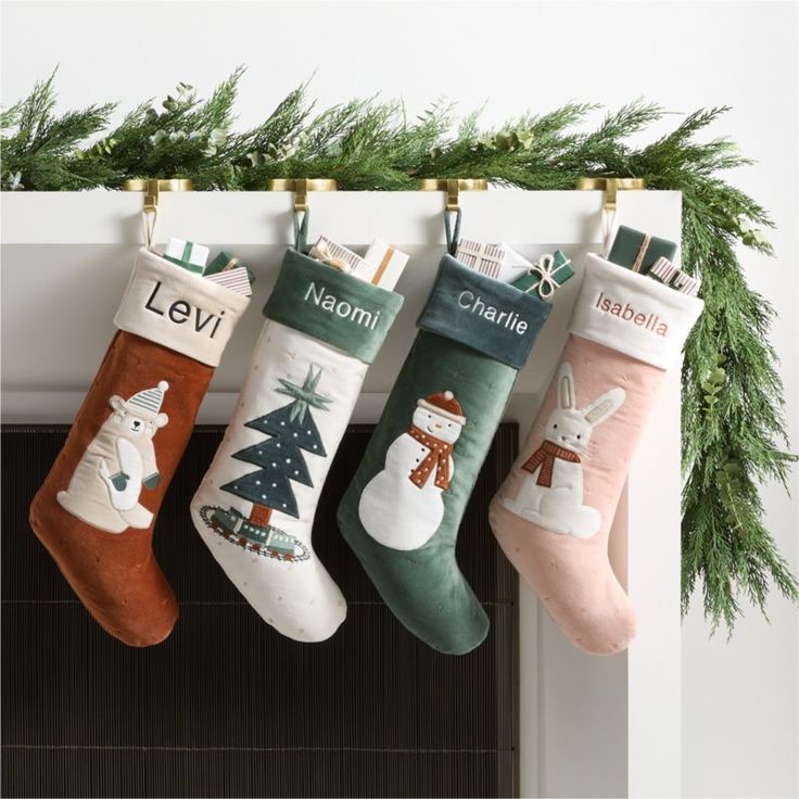 three stockings hanging from a mantel decorated with christmas decorations