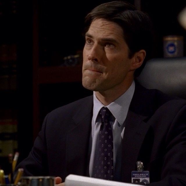 a man in a suit and tie sitting at a table with a book on it